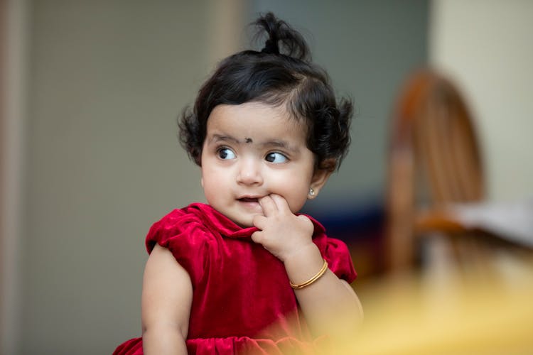 A Little Girl With Her Fingers In Her Mouth