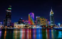 胡志明市的天际线在夜晚灯火璀璨，五光十色的倒影映在河面上，令人惊叹
