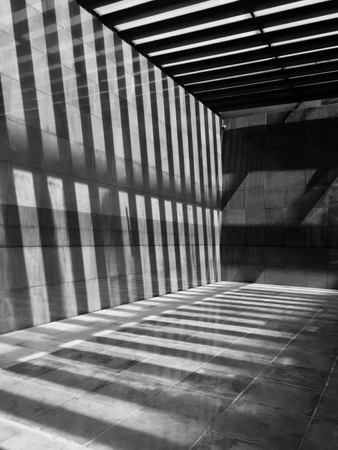 Black and white image of modern architecture with striking sunlight and shadows in Bucharest.