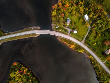 Stunning aerial shot of a bridge traversing a lake surrounded by vibrant autumn foliage in Pictou, NS, Canada.