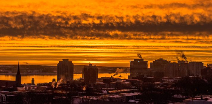 City skyline with vibrant, golden sunset casting dramatic clouds over the landscape.