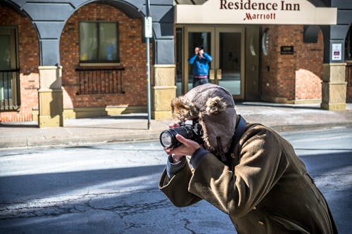 Person in Brown Coat and Hat Holding Black DSLR Camera