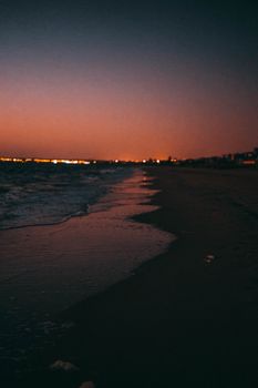 A tranquil beach at twilight with a vibrant sunset sky and gentle waves.