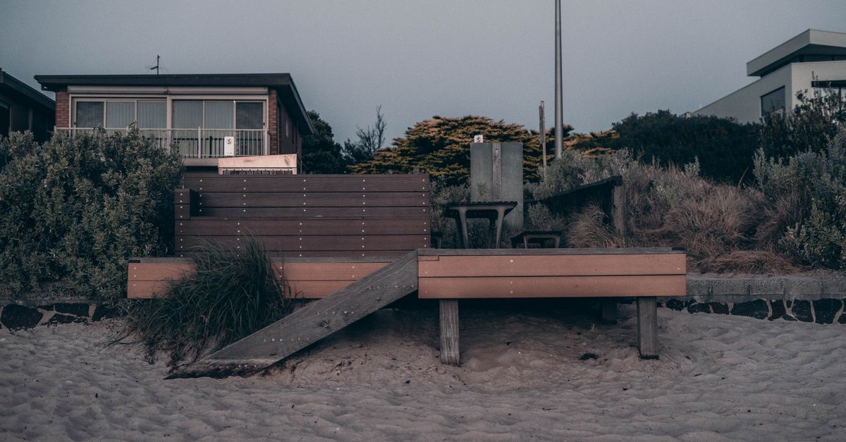 Serene beachfront view featuring sandy shores and cozy wooden decking.