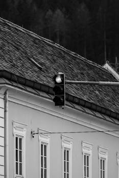 Black and white image of a traffic light and building facade.