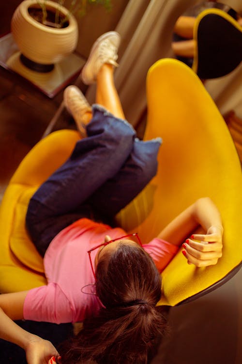 Woman in Pink Shirt Sitting on Yellow Chair