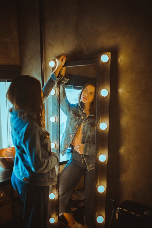 A Woman in Denim Jacket Looking at the Mirror