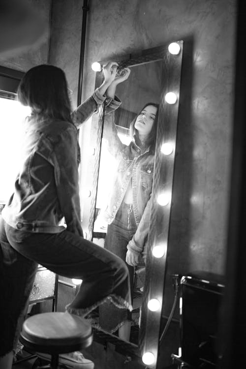 Woman in Jean Jacket Holding a Wall Mirror