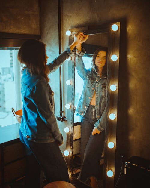 Woman in Blue Denim Jacket Standing in Front of Mirror