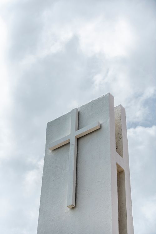Free Vertical shot of a white cross monument against a cloudy sky, symbolizing faith and religion. Stock Photo