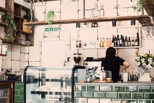 Free Charming café interior showcasing a barista preparing coffee behind the counter. Stock Photo