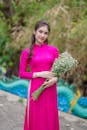 Woman in Pink Long Sleeve Dress Holding Bouquet of Flowers