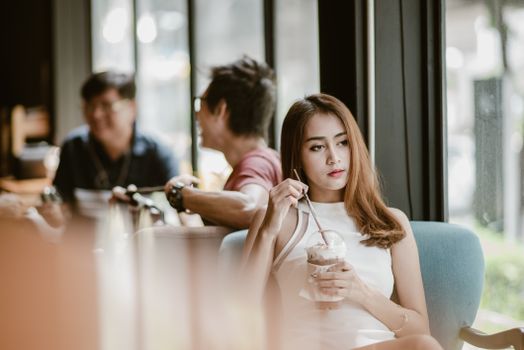 Young woman in a white dress enjoying a beverage in a modern cafe.