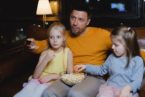 Free Man Watching Television with Children Stock Photo