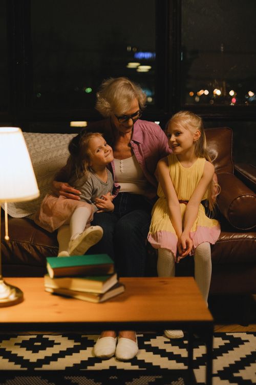 Free Grandmother bonding with granddaughters in cozy living room setting. Stock Photo