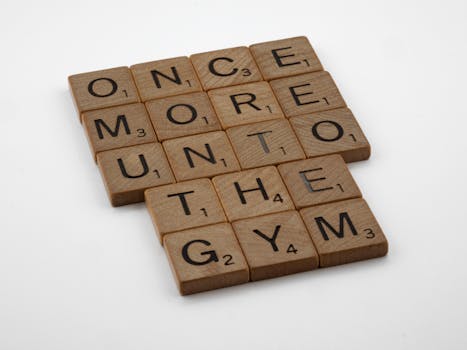 Wooden Scrabble tiles on a white surface spell a motivational quote, ideal for creative projects.