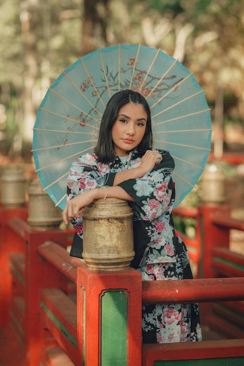 A Woman Leaning on a Fence Post while Holding a Parasol