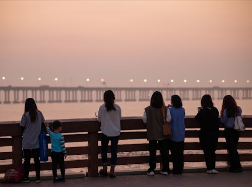 People Standing on Wooden Bridge During Sunset