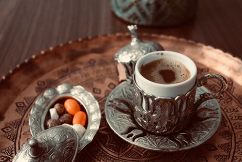 Free Close-up of Turkish coffee served in ornate silverware alongside colorful candies on a decorative tray. Stock Photo