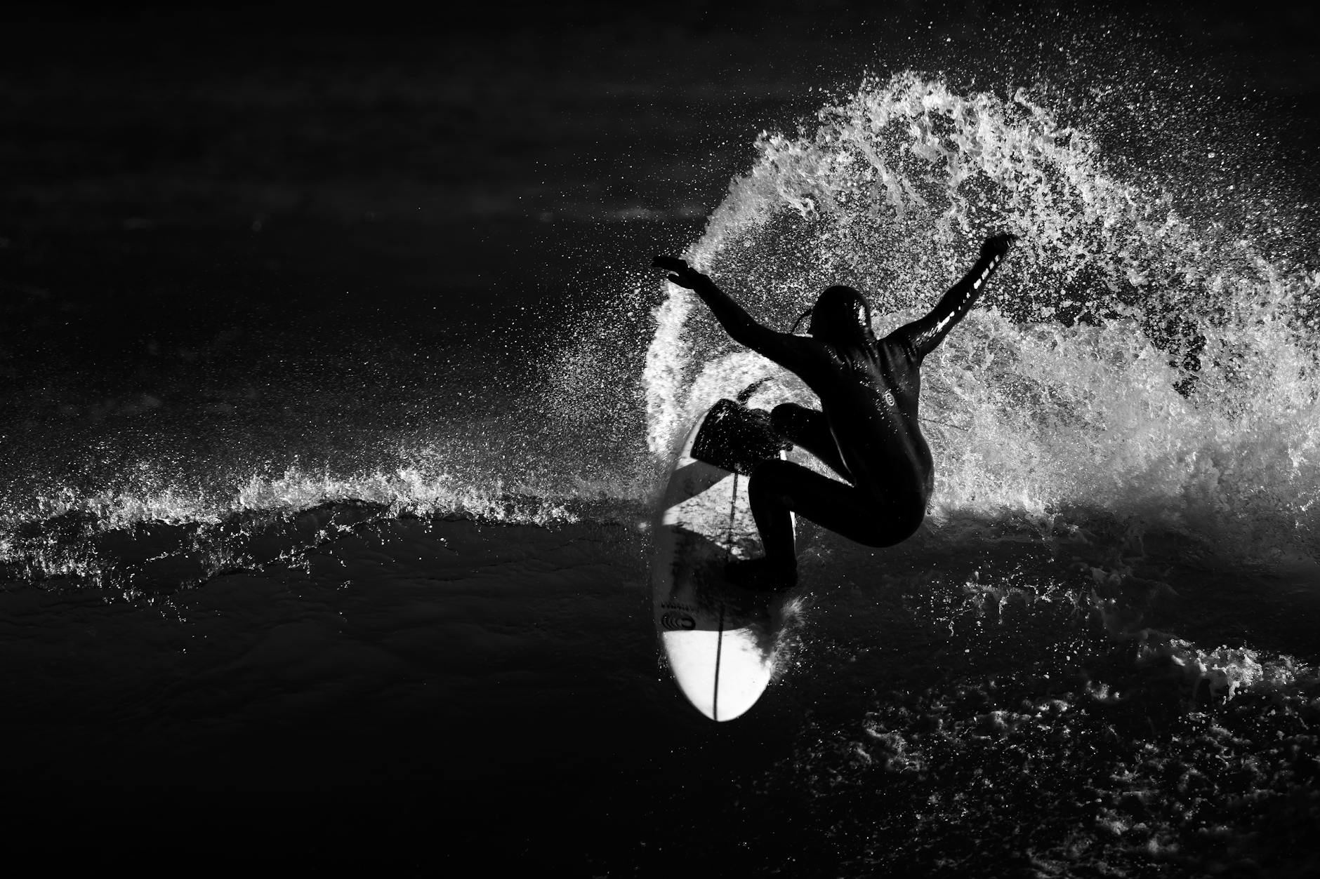 Silhouette of a surfer catching a wave in grayscale, capturing the essence of adventure and skill.