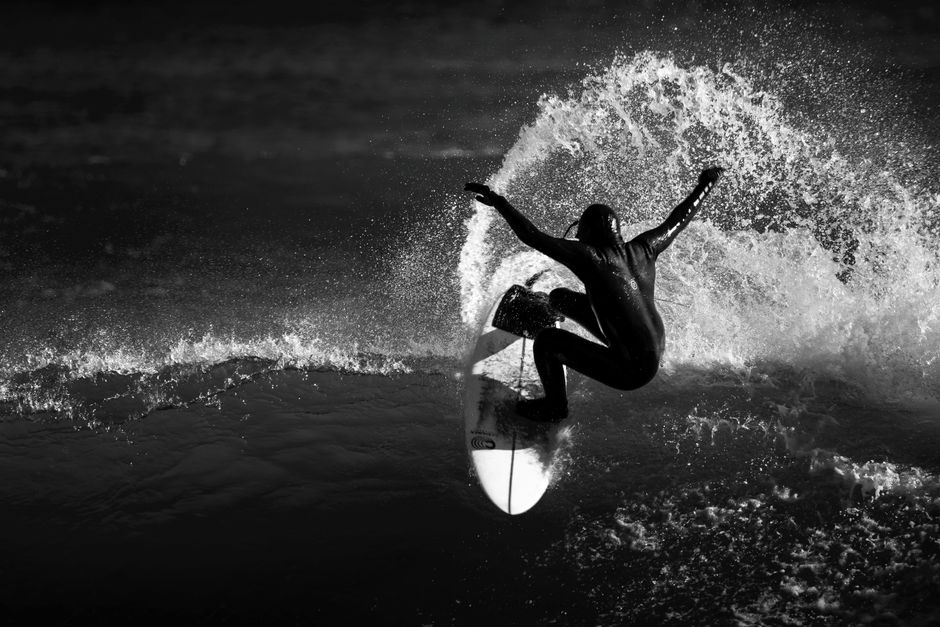 Silhouette of a surfer catching a wave in grayscale, capturing the essence of adventure and skill.