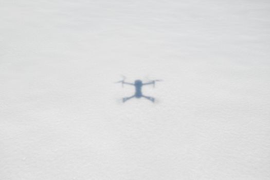 Blurred drone shadow on a snowy ground, illustrating aerial photography.