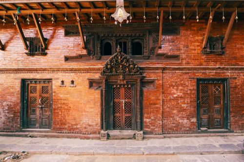Free Red brick facade with intricately carved wooden doors, showcasing traditional architecture. Stock Photo