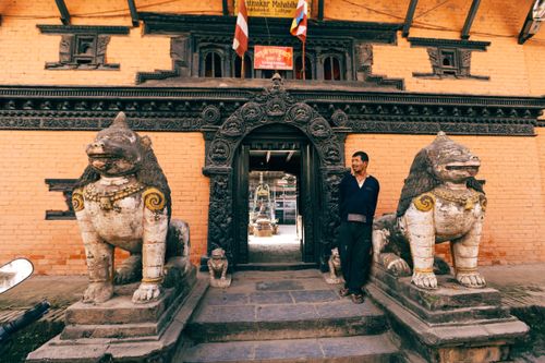 Free A man stands by a traditional temple entrance in Nepal, flanked by guardian statues. Stock Photo
