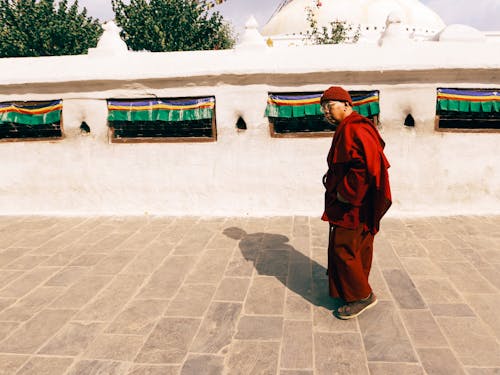 Elderly Monk Walking in Front of a Temple 