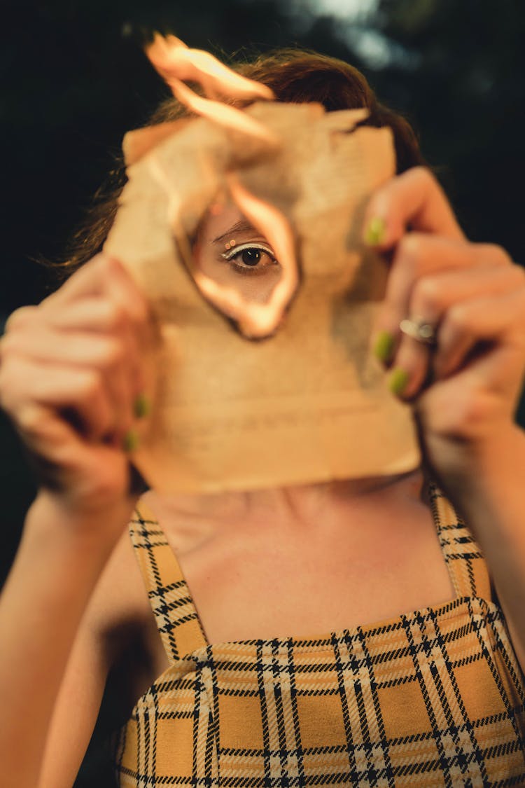 Selective Focus Photo Of Person's Eye Through A Hole Of A Burning Paper 