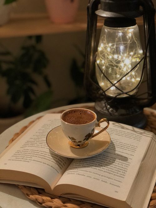 Free A warm ambiance featuring Turkish coffee with a glowing lantern and open book. Stock Photo