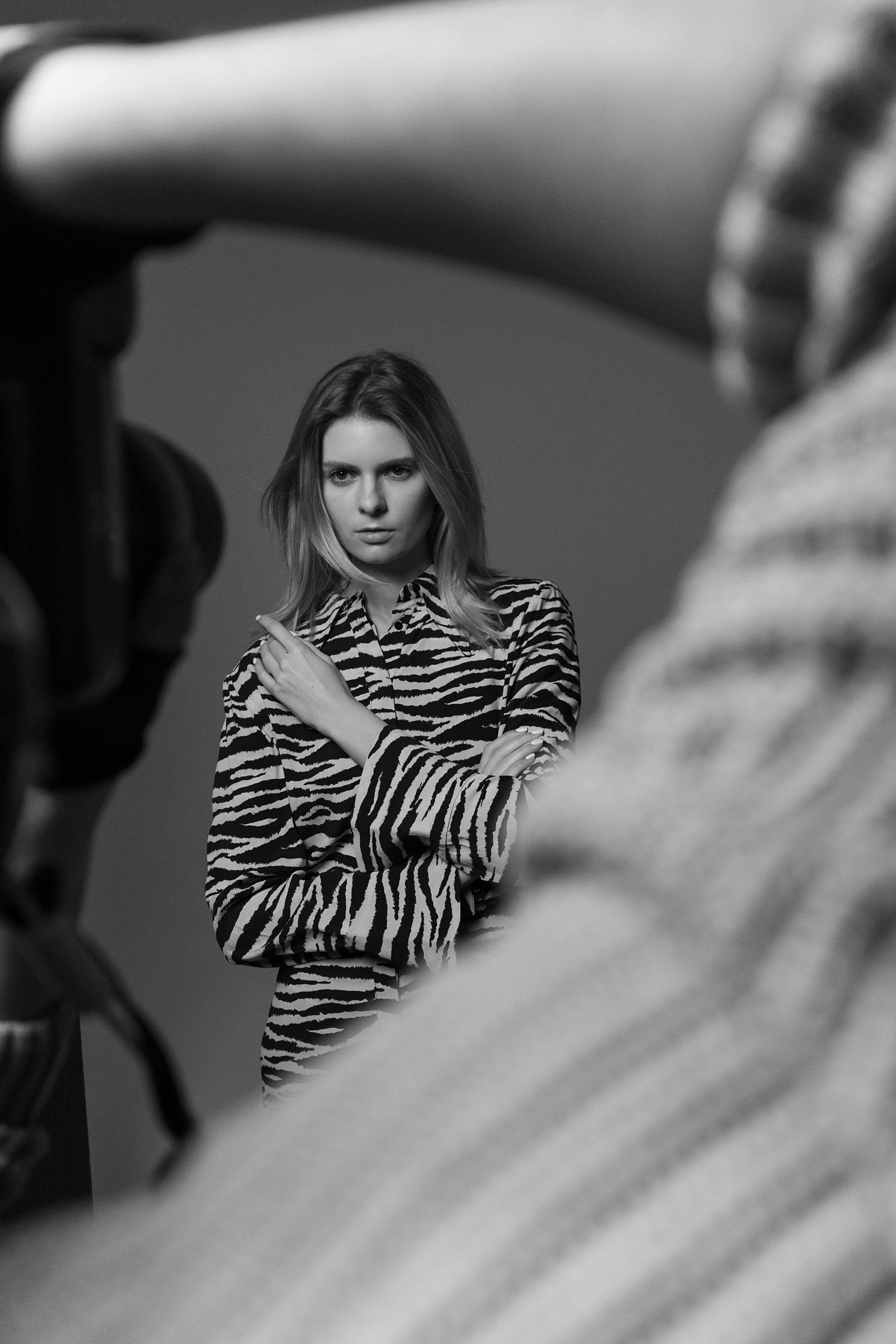 Black-and-white studio photoshoot featuring a model in zebra print attire captured with a camera in foreground.