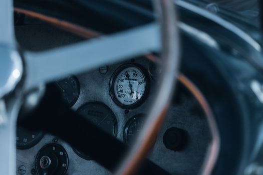 Vintage car dashboard featuring gauges and dials behind a steering wheel.