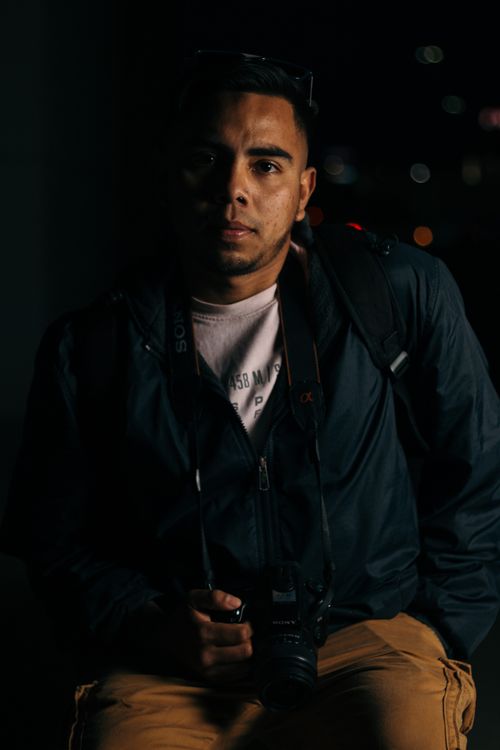 Free Moody portrait of a photographer holding a camera in low light. Stock Photo