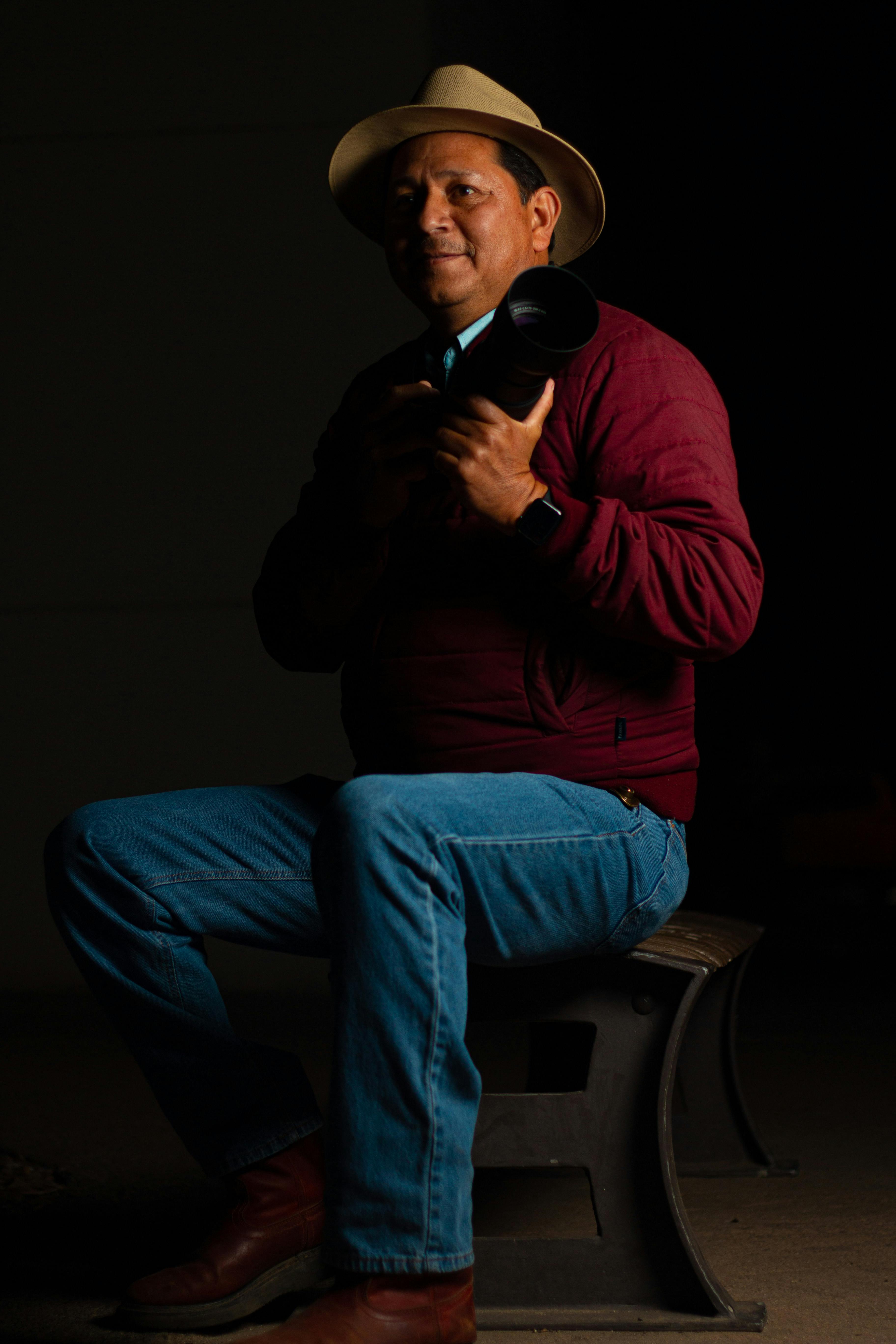 Middle-aged photographer sitting in a studio with a camera, creating a classic portrait.