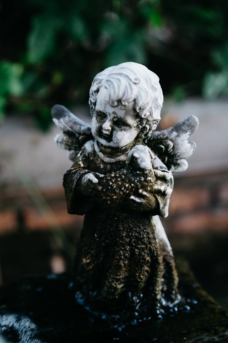 An Angel Statue Holding Baby Sheep