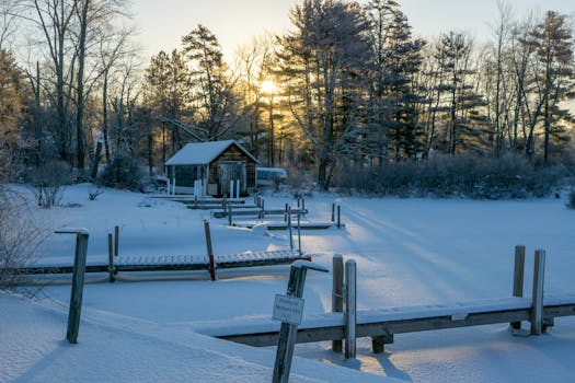 A serene winter morning with a frozen lake and dock, beautifully lit by sunrise.