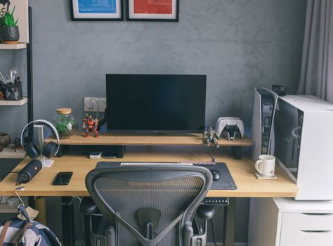 Stylish home office with tech gadgets, computer, and gaming console on a wooden desk.