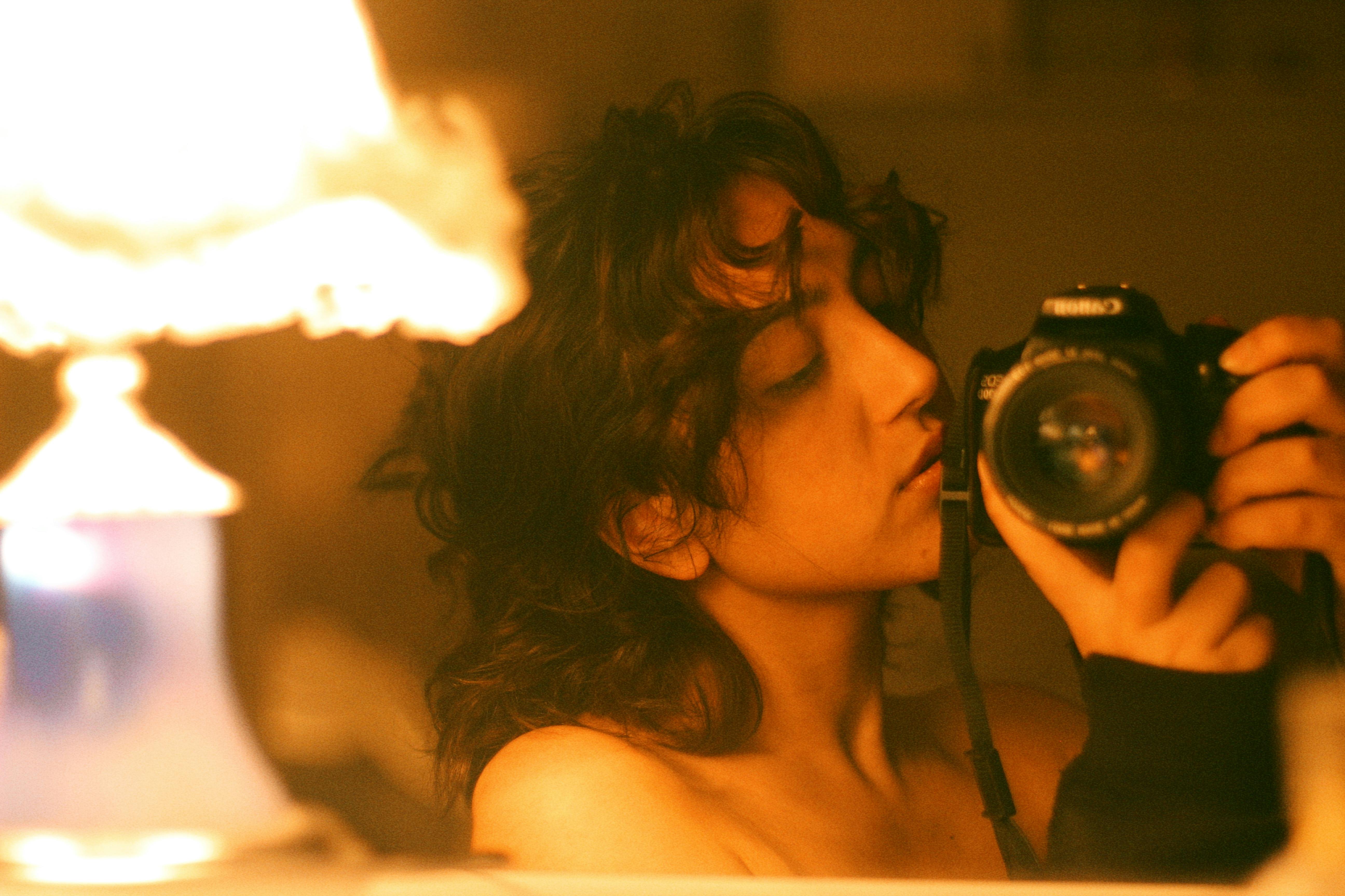 Vintage-style portrait of a woman holding a camera in warm lighting.