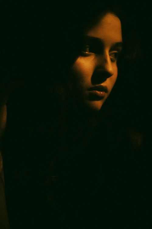 Free A dramatic low-light portrait of a woman with a dark, moody atmosphere. Stock Photo