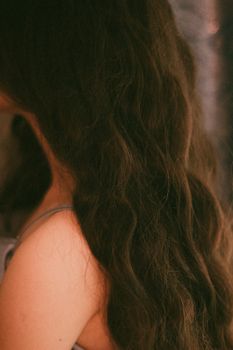 A vertical close-up of a woman with long, flowing dark hair in natural light.