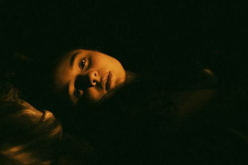 Free A mysterious low-light portrait capturing a woman's serene expression. Stock Photo