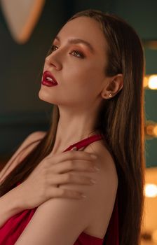Close-up portrait of a woman with striking red lips and elegant pose, captured in a softly lit environment.