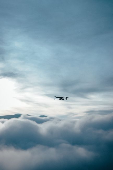 A drone captured flying high above dense clouds, showcasing modern aviation technology and serene sky.