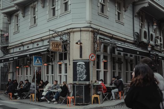 Café confortable avec des personnes profitant d'un espace extérieur au coin d'une rue.