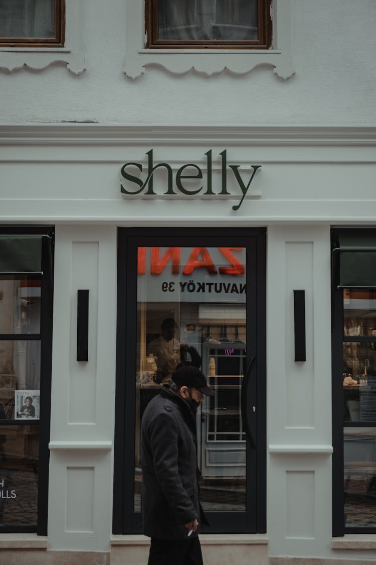 A Man Walking In Front Of A Store