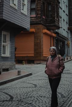 A woman walking down a brick road in a city, surrounded by urban architecture.