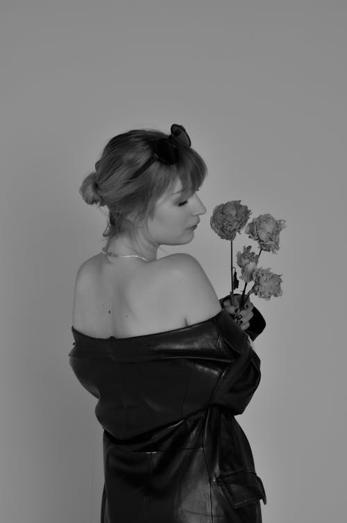 Grayscale Photo of a Woman Holding Flowers