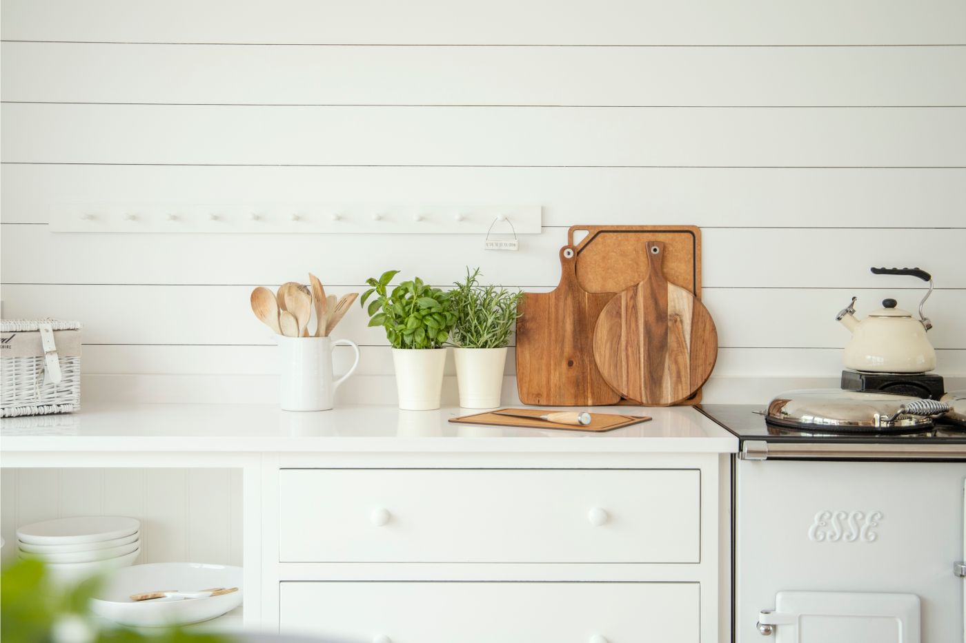Potted basil and rosemary beside wooden kitchen utensils