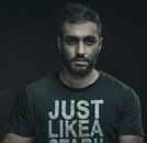 Moody portrait of a bearded man wearing a black t-shirt against a dark background.